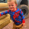 child, boy, spiderman_shirt, face, mud, car_door, vehicle, tire, outdoor, pants, expression, standing, playful, dirt, casual_clothing, portrait, young, person, fun, grit