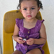 Eliana joined the competition — help win amazing prizes! bright_colors, buttoned_top, casual_clothing, child, curious, curly_hair, cute, face, indoor, person, portrait, purple_outfit, serious_expression, sitting, skin, small_hands, toddler, toy, yellow_chair, young_child