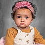 toddler, child, face, headband, pink, flower, curly_hair, mustard, long_sleeve, dress, buttons, floral_pattern, portrait, studio, expression, pout, cute, person, seated, blanket