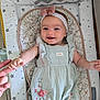 baby, infant, smile, holding_hand, headband, bow, romper, floral, duck, baby_mat, pattern, star_pattern, hand, cute, happy, lying_down, indoors, person, child, soft_lighting
