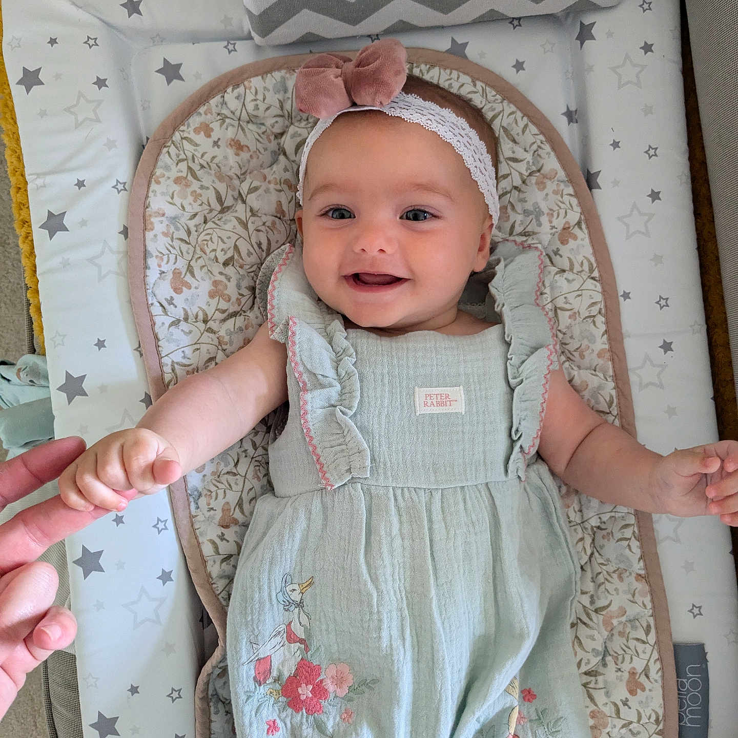 Birdy is registered to the contest to win money with this photo: baby, baby_mat, bow, child, cute, duck, floral, hand, happy, headband, holding_hand, indoors, infant, lying_down, pattern, person, romper, smile, soft_lighting, star_pattern