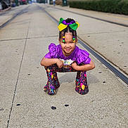Jaliyah joined the competition — help win amazing prizes! child, city, clothing, costume, dress, face, female, girl, head, pants, path, person, photography, portrait, purple, road, sidewalk, sitting, street, urban
