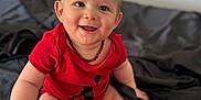 Noélio participe au concours pour gagner de l'argent avec cette photo : baby, bed, black_socks, child, clothing, cute, face, happy, head, indoor, infant, person, playing, plush_toy, portrait, red_onesie, sitting, skin, smiling, young