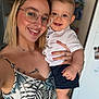 Noélio a rejoint le concours — aidez-le/la à gagner de superbes lots ! baby, background_blur, child, face, glasses, hand, happy, holding, home, indoor, necklace, person, portrait, shorts, skin, smile, tattoo, tropical_dress, white_shirt, woman