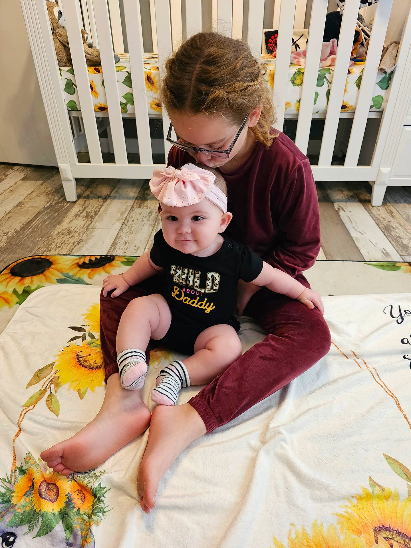 Aubree joined the competition — help win amazing prizes! baby, child, event, fence, fun, grass, happy, headwear, human_leg, knee, lap, leisure, linens, person, plant, shorts, sitting, sneakers, sock, t_shirt