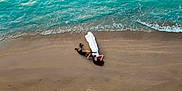 Maïko participe au concours pour gagner de l'argent avec cette photo : beach, sand, ocean, waves, woman, dog, white_dress, lying_down, aerial_view, nature, water, shore, relaxation, companionship, outdoor, summer, peaceful, vacation, animal, friendship