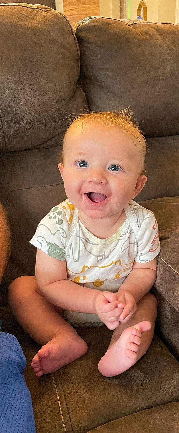 Tanner is registered to the contest to win money with this photo: arm, baby, baby_toddler_clothing, cheek, chin, comfort, finger, flooring, fun, happy, human, human_body, mouth, nose, person, pink, skin, sleeve, smile, thumb