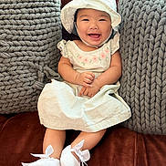 Karleen Renee joined the competition — help win amazing prizes! baby, child, smiling, dress, hat, bonnet, couch, pillow, knit_pillow, white_shoes, bows, happy, indoor, portrait, seated, furniture, cute, infant, person, cozy
