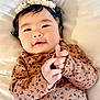 Karleen Renee is registered to the contest to win money with this photo: baby, infant, child, face, hands, headband, patterned_clothing, brown_clothing, lying_down, soft_surface, cute, smiling, closeup, portrait, indoors, curly_hair, happy, skin, tiny_hands, flower_crown