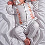 baby, infant, pacifier, white_clothing, bed, bedding, sleepwear, child, portrait, cute, newborn, relaxed, lying_down, soft_texture, indoors, peaceful, small_feet, curly_hair, orange_text, skin