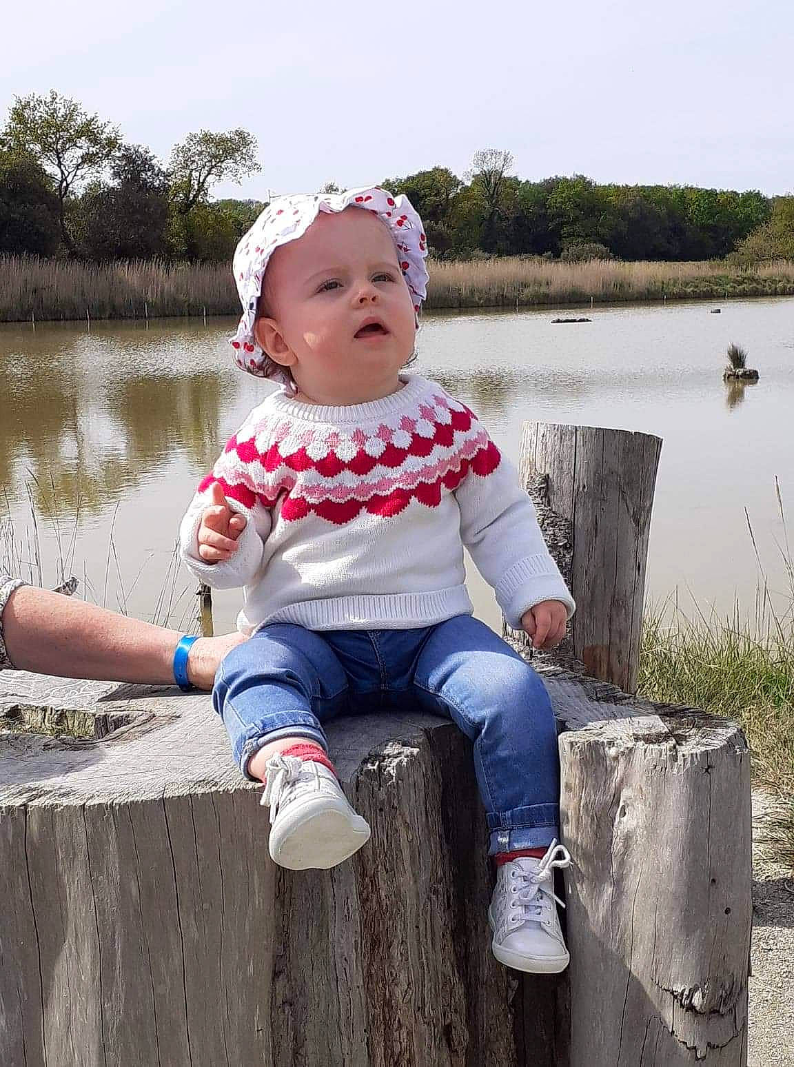 Alyna participe au concours pour gagner de l'argent avec cette photo : baby, baby_toddler_clothing, child, fun, grass, happy, headwear, lake, leisure, people_in_nature, person, pink, plant, recreation, shoe, sitting, sky, sneakers, summer, toddler
