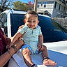 anklets, baby, blue_sky, car, child, cute, face, fence, hands, happy, house, outdoor, person, shirt, shorts, sitting, smiling, sunny_day, tree, white_car