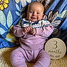 baby, blanket, child, closeup, cozy, family_photo, floral_blanket, hands, happy, indoor, infant, milestone, pink_outfit, portrait, reclining, sitting, smiling, sweater, three_months, wooden_sign