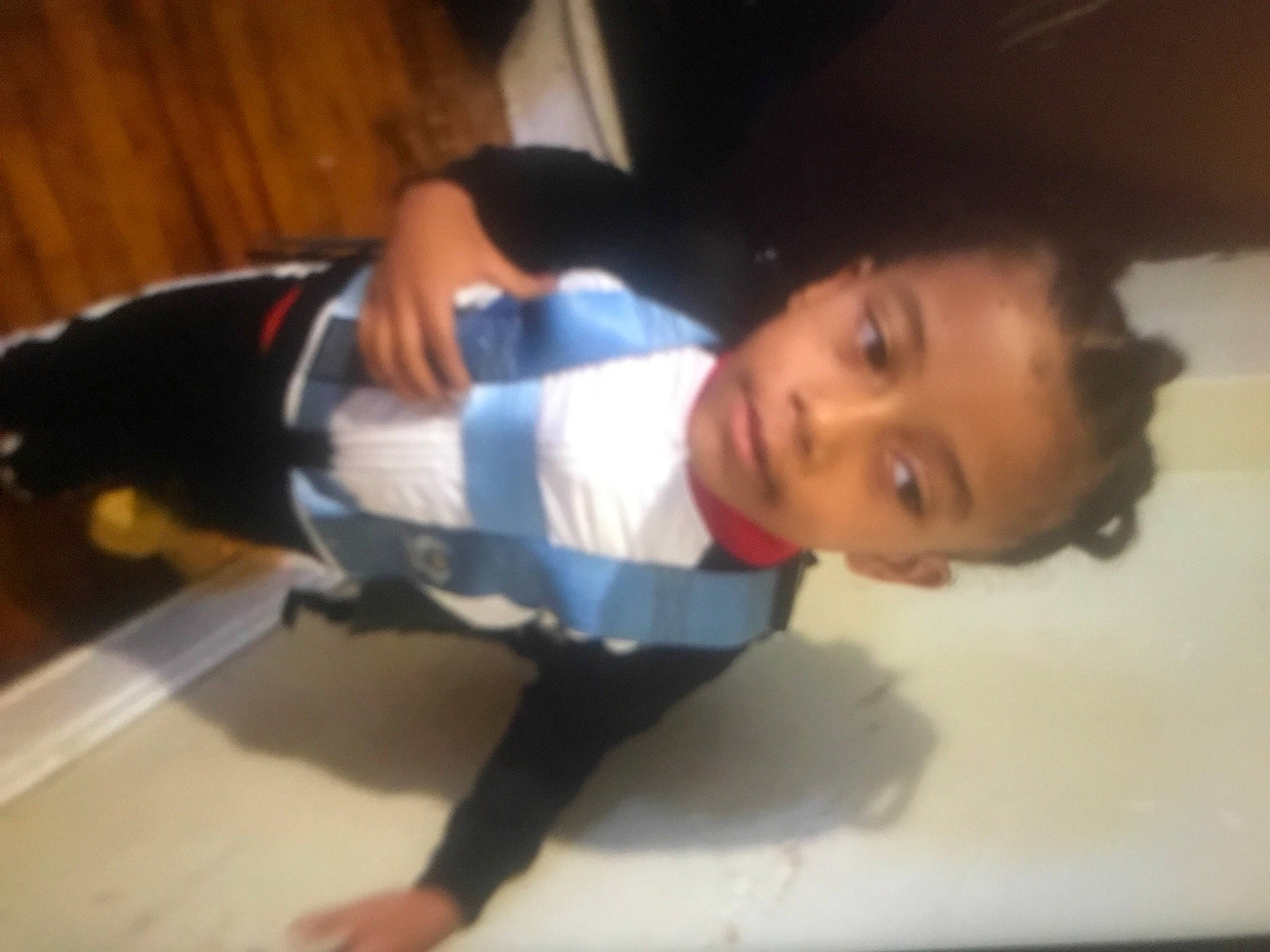 Jordan is registered to the contest to win money with this photo: cleanliness, comfort, elbow, electric_blue, eye, flooring, fun, hardwood, human_leg, knee, nose, person, room, sitting, sleeve, thigh, thumb, trunk, uniform, wood