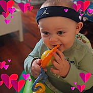 Kason joined the competition — help win amazing prizes! baby, child, headband, toy, indoor, heart_graphics, chewing, cute, infant, hand, face, blue_eyes, green_clothing, blurred_background, wood_floor, love, playful, closeup, person, happy