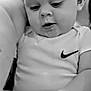 baby, infant, child, onesie, nike_logo, black_and_white, close_up, hand, person, cute, portrait, soft_light, indoor, looking_down, expression, face, human, skin, arm, apparel