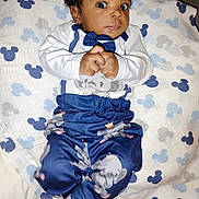 Adore is registered to the contest to win money with this photo: baby, infant, child, clothing, elephant_print, bow_tie, blanket, mickey_mouse_pattern, bed, pajamas, cute, curious, hands_clasped, lying_down, indoors, person, face, wide_eyes, soft_texture, sleepwear