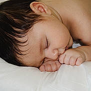 Maverick is registered to the contest to win money with this photo: baby, sleeping, infant, close_up, face, hand, skin, hair, pillow, rest, peaceful, cute, child, newborn, soft, natural_light, portrait, relaxation, fingers, person