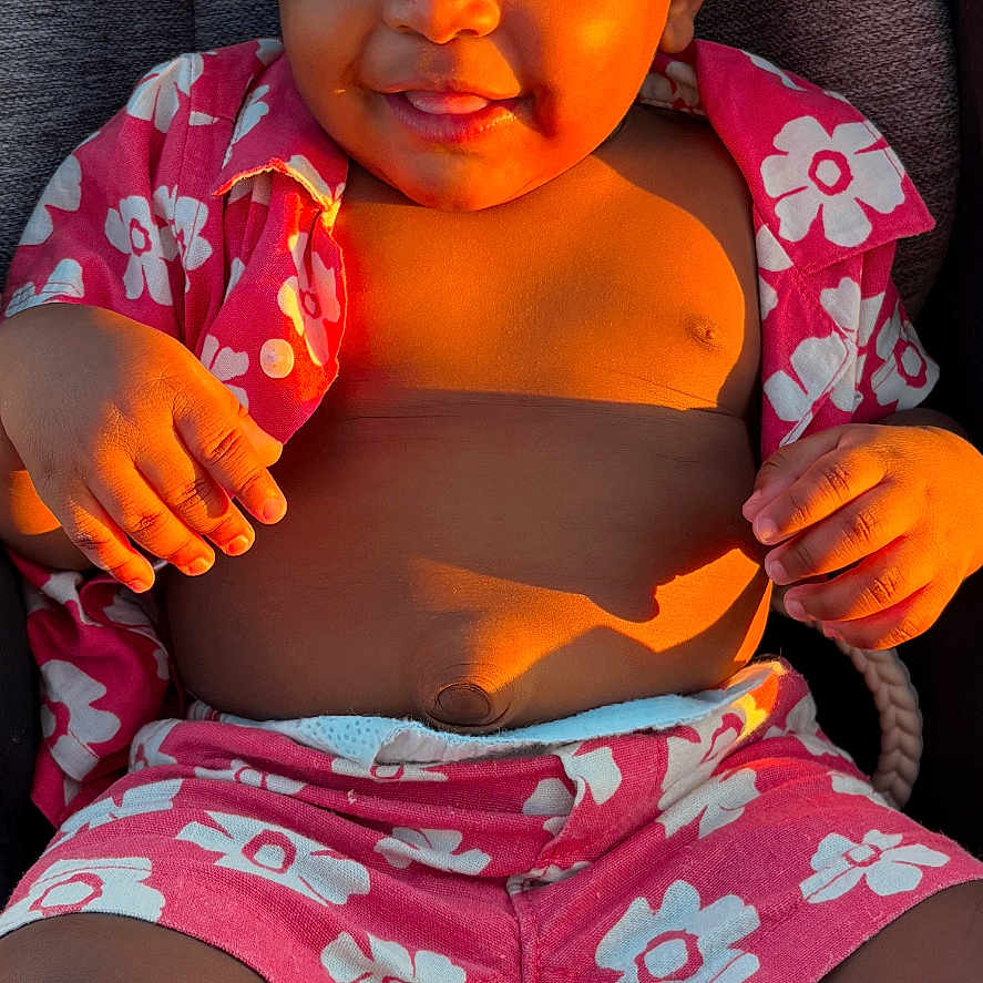 Amazi joined the competition — help win amazing prizes! baby, casual, child, cute, expression, face, floral_pattern, hand, happy, infant, legs, outdoor_light, pink_clothing, portrait, seat, shadow, sitting, skin, smiling, sunlight