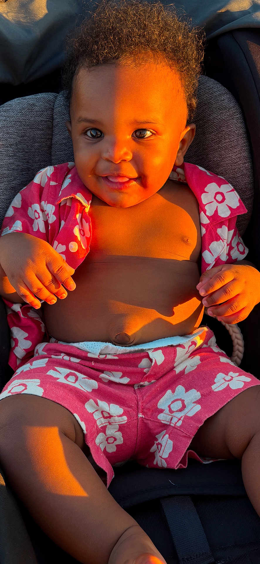 Amazi joined the competition — help win amazing prizes! baby, child, smiling, sunlight, pink_clothing, floral_pattern, sitting, happy, cute, portrait, infant, skin, hand, face, legs, seat, shadow, outdoor_light, casual, expression