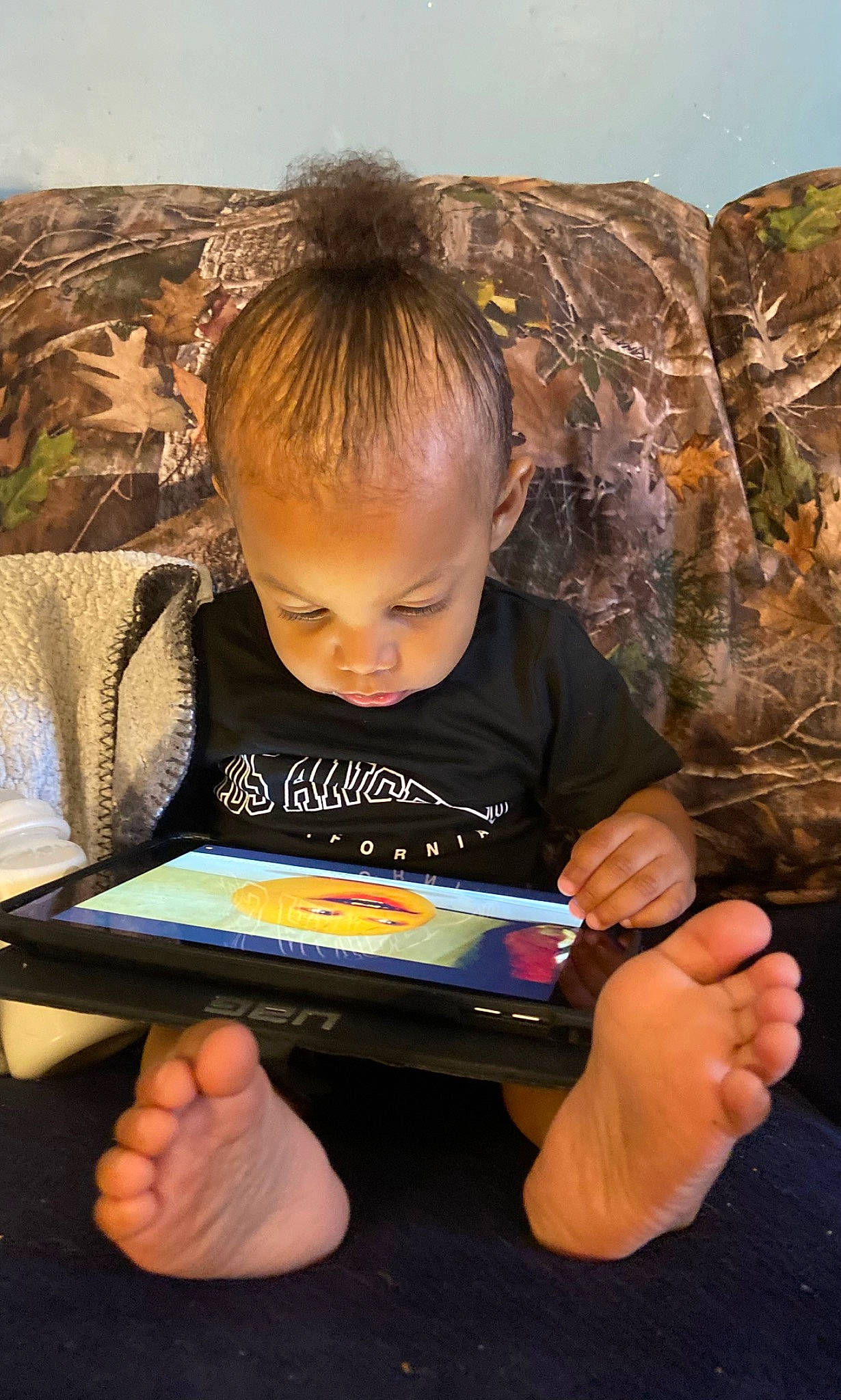 Messiah is registered to the contest to win money with this photo: child, couch, finger, fun, gadget, hand, happy, learning, person, play, publication, reading, room, sharing, sitting, smile, t_shirt, tablet_computer, thumb, toddler