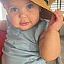 baby, child, hat, straw_hat, cute, indoor, blue_clothing, face, eyes, hand, curious, smiling_hat, person, portrait, sitting, young_child, infant, plush_hat, expression, closeup