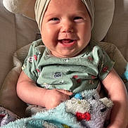 Aurora joined the competition — help win amazing prizes! baby, smiling, headband, blanket, green_shirt, cushion, happy, infant, cute, indoor, child, portrait, fuzzy_blanket, seated, clothing, baby_girl, expression, headwear, comfort, closeup