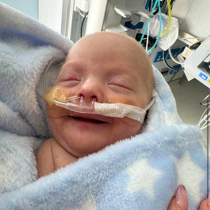 Cai is registered to the contest to win money with this photo: architecture, baby, bed, blanket, bodypart, building, clinic, clothing, face, finger, furniture, glove, hand, head, hospital, newborn, operatingtheatre, person, photography, portrait