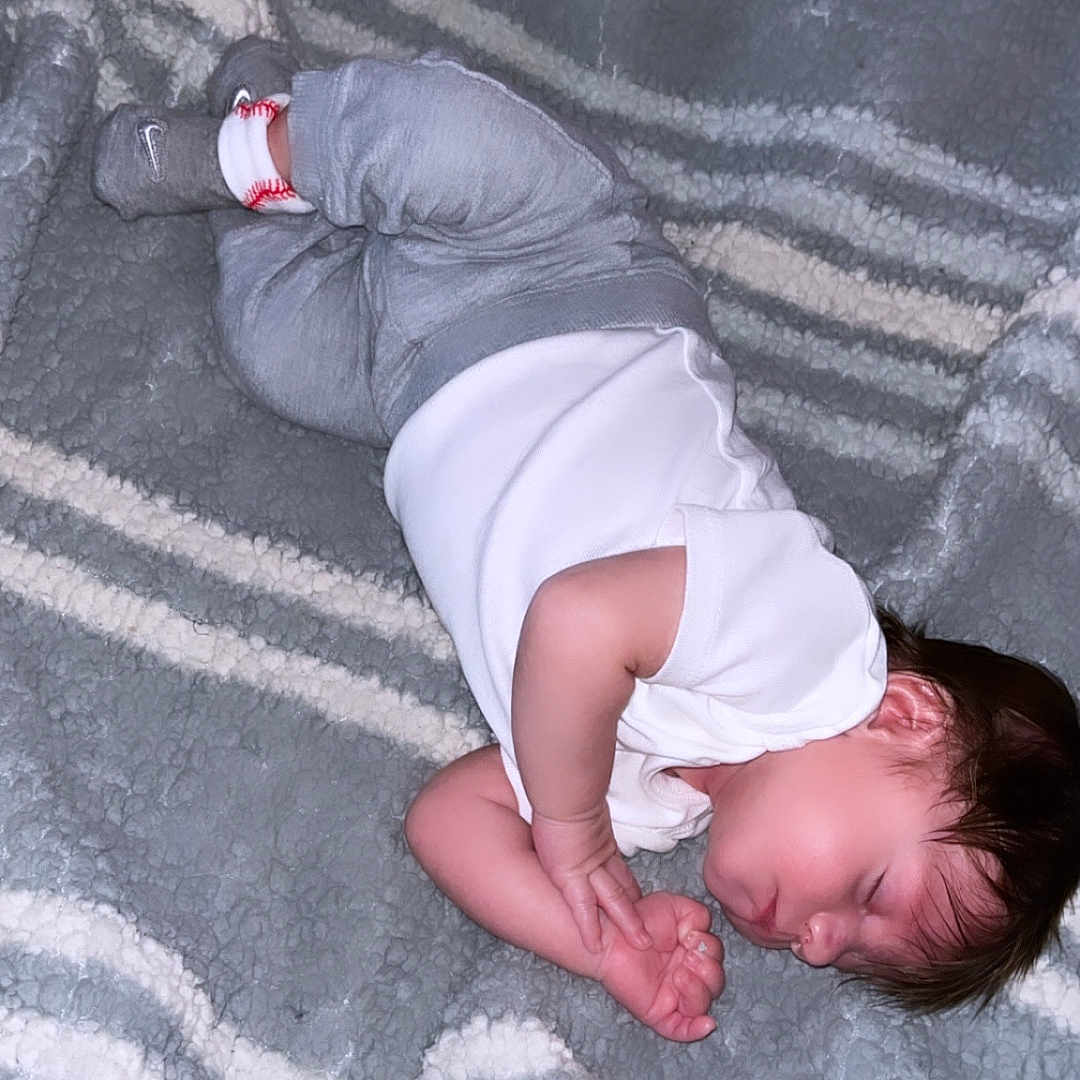 Kashdon is registered to the contest to win money with this photo: baby, bedtime, blanket, child, comfort, cozy, cute, gray_pants, hair, indoors, infant, peaceful, portrait, resting, skin, sleeping, soft, striped_blanket, toddler, white_clothing