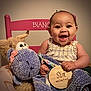 baby, child, smiling, teddy_bear, stuffed_animal, chair, pink, wooden_sign, six_months, happy, infant, cute, portrait, indoor, face, person, clothing, plush, holding, sitting