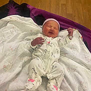 Ryverlynn Rose is registered to the contest to win money with this photo: newborn, baby, sleeping, onesie, slippers, blanket, floor, wooden_floor, infant, cute, child, cozy, soft, clothing, lying_down, indoors, peaceful, adorable, headwear, resting