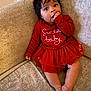 baby, child, infant, red_dress, couch, furniture, indoors, cute, festive, holiday, sitting, hand, face, hair, skin, expression, comfort, toddler, young, portrait