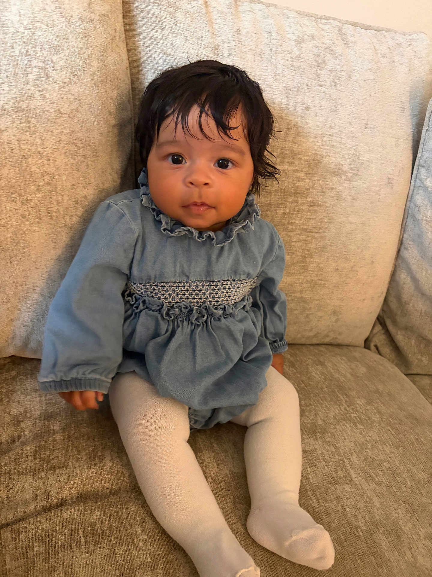 Addison joined the competition — help win amazing prizes! baby, child, infant, couch, blue_dress, white_tights, sitting, indoors, face, person, cute, young, portrait, looking_at_camera, furniture, soft_lighting, comfortable, homedecor, curly_hair, curious