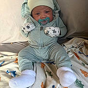 Jakarri joined the competition — help win amazing prizes! baby, infant, child, portrait, sitting, pacifier, hat, animal_hat, mittens, star_pattern, onesie, winter_clothing, socks, blanket, dinosaur_blanket, bed, indoor, cozy, looking_at_camera, baby_portrait