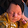 Montana is registered to the contest to win money with this photo: baby, sleeping, headband, bow, black, mustard_yellow, floral_pattern, outfit, clothing, hand, tattoo, skin, face, peaceful, closeup, infant, person, resting, indoors, warm_light