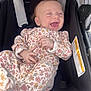 baby, infant, smiling, laughing, floral_clothing, onesie, stroller, child, cute, happy, sitting, person, face, hand, foot, fabric, seat, black, comfort, joy