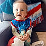 baby, child, plush_toy, bib, striped_clothing, couch, blanket, crocheted_throw, blue, red, white, teal, happy, smiling, indoors, person, sitting, sock, cute, soft_toy