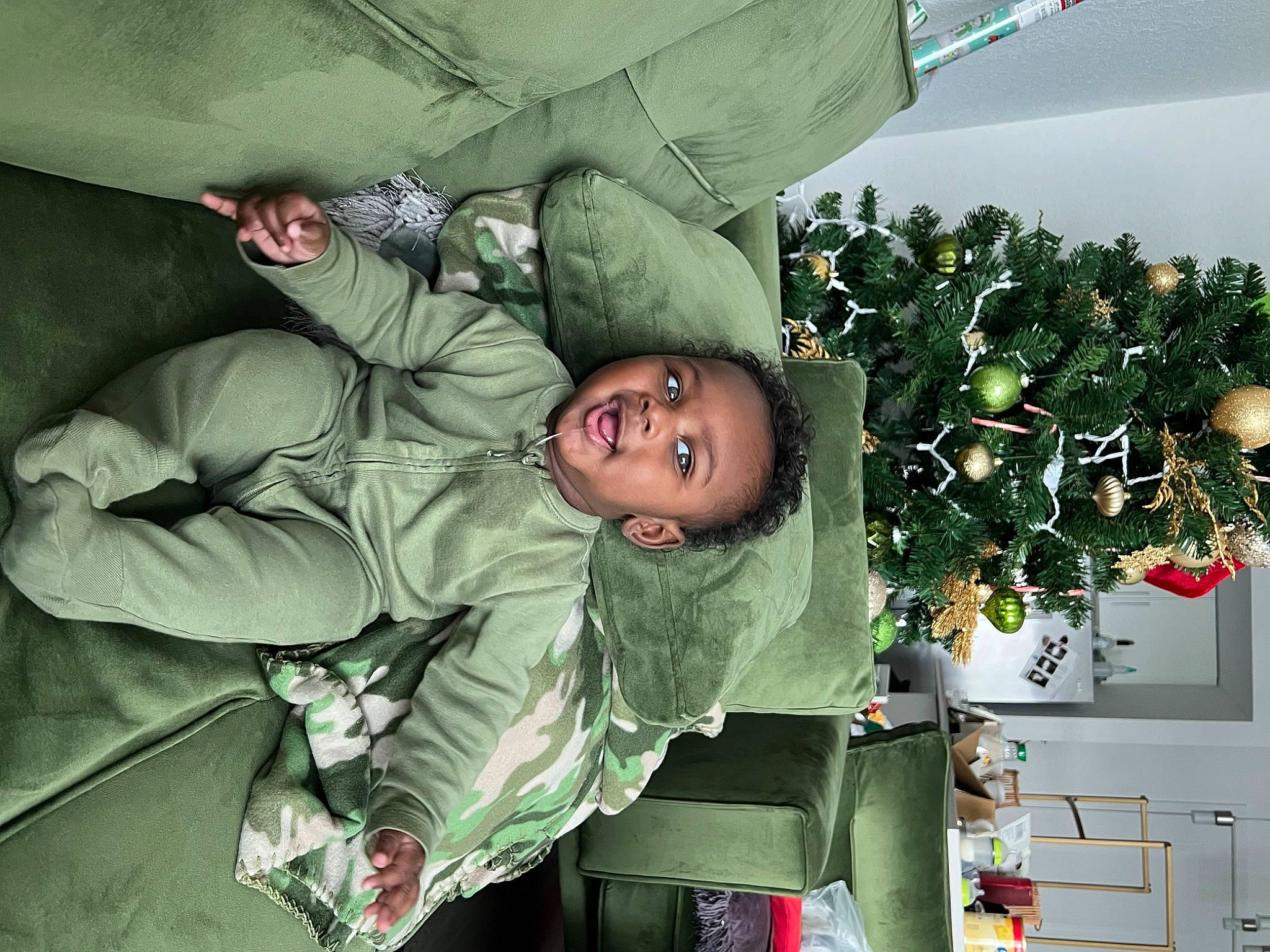 Cree is registered to the contest to win money with this photo: camouflage, child, christmas_ornament, christmas_tree, comfort, event, fun, holiday, houseplant, human_body, jacket, military_camouflage, military_organization, military_person, military_uniform, non_commissioned_officer, person, room, shelf, soldier