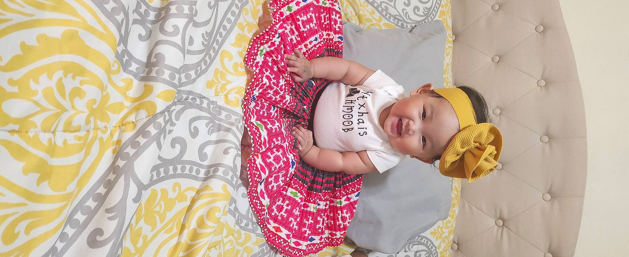 Mila is registered to the contest to win money with this photo: art, baby, baby_toddler_clothing, child, comfort, fashion_accessory, happy, hat, headwear, linens, magenta, pattern, peach, person, room, sleeve, smile, textile, toddler, visual_arts