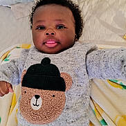 Nathan a rejoint le concours — aidez-le/la à gagner de superbes lots ! baby, infant, child, cute, smiling, tongue_out, curly_hair, sweater, bear_design, knitwear, blanket, soft_texture, lying_down, indoors, portrait, adorable, happy, face, closeup, cozy