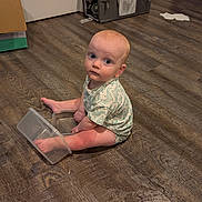 James joined the competition — help win amazing prizes! baby, child, floor, wooden_floor, plastic_container, foot, sitting, indoor, curious, looking_up, onesie, clothing, blue_eyes, light_skin, expression, home, room, door, box, flooring