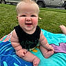 baby, child, outdoor, grass, towel, funny_face, sitting, cute, blond_hair, expression, skin, foot, hand, vehicle, car, house, lawn, summer, playtime, casual_clothing