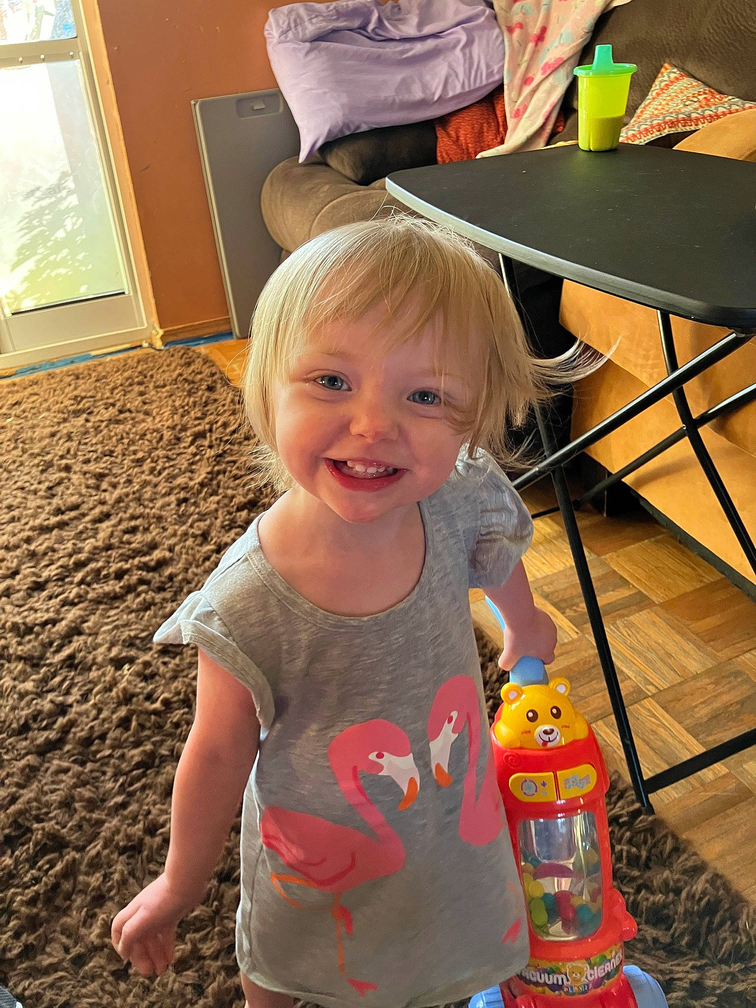 Harlow is registered to the contest to win money with this photo: blond, chair, child, door, flooring, fun, happy, joy, laugh, leisure, person, play, recreation, room, sitting, smile, standing, t_shirt, table, toddler