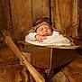 aviator_hat, baby, blanket, child, cozy, cute, hat, infant, knit_hat, newborn, peaceful, portrait, prop, resting, sleeping, studio_photo, wood_background, wood_floor, wood_tones, wooden_airplane