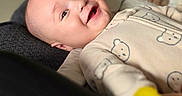 Julyan is registered to the contest to win money with this photo: baby, child, smiling, onesie, toy, indoor, furniture, chair, blurred_background, happy, infant, person, cute, cozy, home, portrait, laying_down, soft_light, face, expression