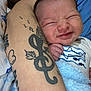 baby, newborn, tattoo, arm, blue_blanket, clothing, face, person, infant, smile, scrunched_face, skin, hand, closeup, indoor, cute, expression, holding, people, child