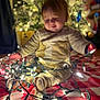baby, child, christmas_tree, christmas_lights, blanket, indoor, holiday, festive, toddler, decorations, lighting, cozy, cute, smiling, sitting, warm, red, white, yellow, celebration