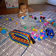 Xeno joined the competition — help win amazing prizes! toddler, child, toy_car, plastic_eggs, basket, mattress, indoor, door, diaper_box, floor, playtime, colorful, curious, sitting, clothing, head, face, hand, footwear, wood_floor