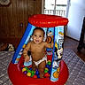 Xeno is registered to the contest to win money with this photo: toddler, child, diaper, inflatable, ball_pit, colorful, smiling, indoor, wood_paneling, window, natural_light, play, toy, balls, cartoon, mickey_mouse, floor, mat, person, happy