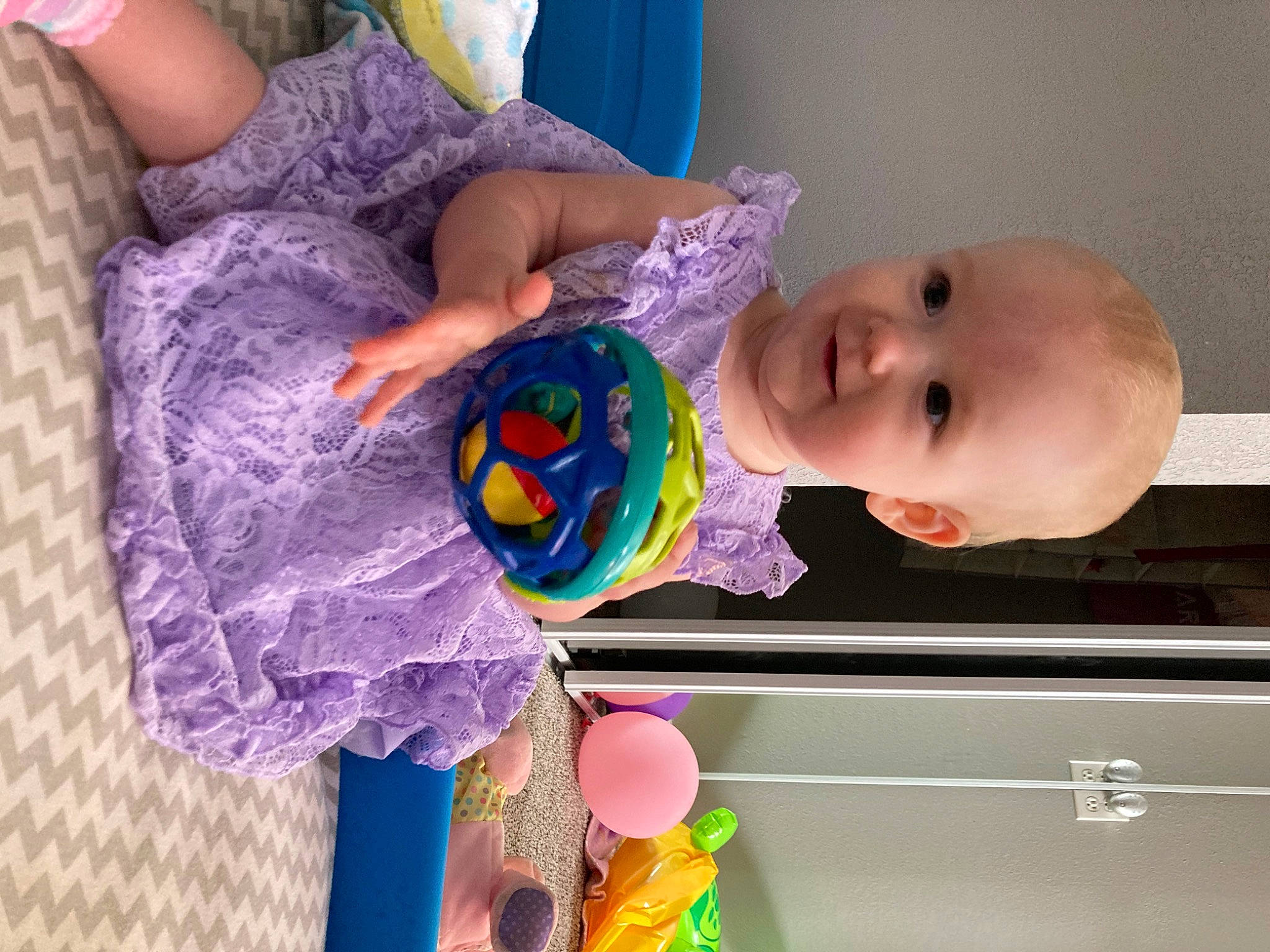 Alianna is registered to the contest to win money with this photo: arm, baby, baby_products, baby_toddler_clothing, baby_toys, cheek, child, dress, green, iris, magenta, pattern, person, pink, purple, room, skin, textile, toddler, violet